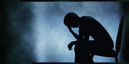 Person sitting in am empty, darkened space in a blue depression